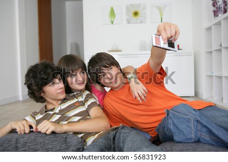 Portrait of teenagers sitting on the floor taking a photo with a mobile phone