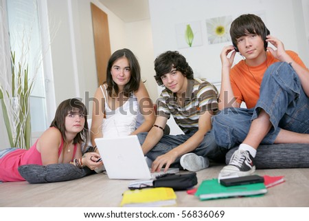 Group of teenagers listening to music near a boy sitting in front of a laptop computer