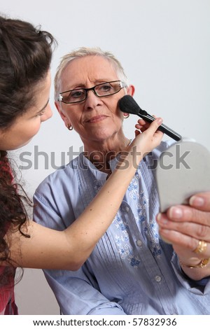 Young woman making up a senior woman