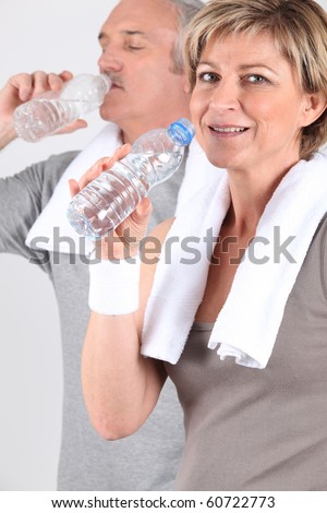 Senior man and senior woman drinking water after sports