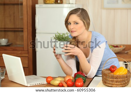 Young woman in kitchen with aromatic plant