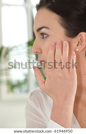 Portrait of a woman applying cream on her face