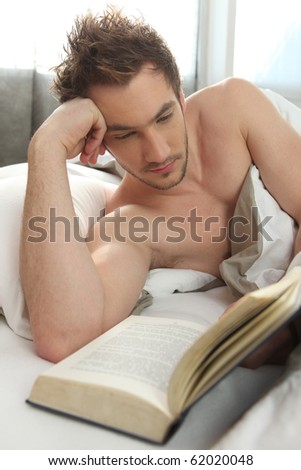 Young man reading a book in bed