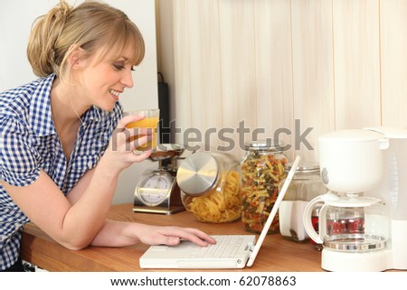 Young woman drinking orange juice in front of a laptop computer