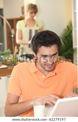Young man in front of a laptop computer in the kitchen