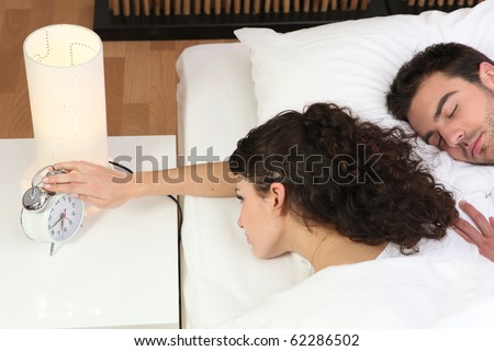 Laid woman watching the alarm clock