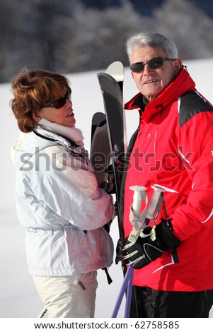 Senior man and senior woman with skis in snow