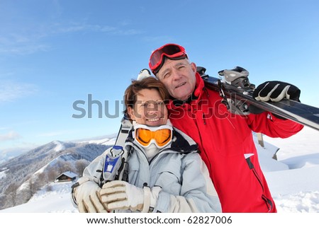 Portrait of a senior man and a senior woman smiling with skis in snow
