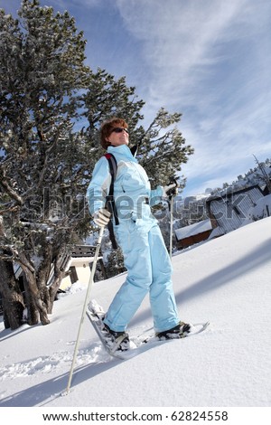 Senior woman smiling with snow-shoes on snow