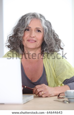 Portrait of a Senior woman smiling in front of a computer