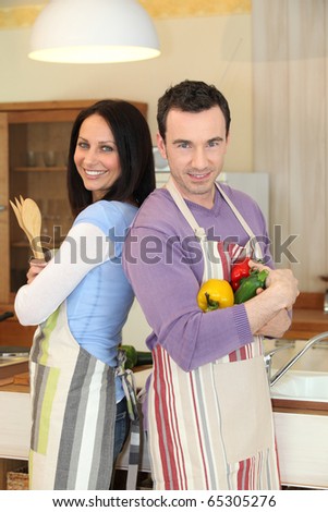 Couple standing back to back in the kitchen