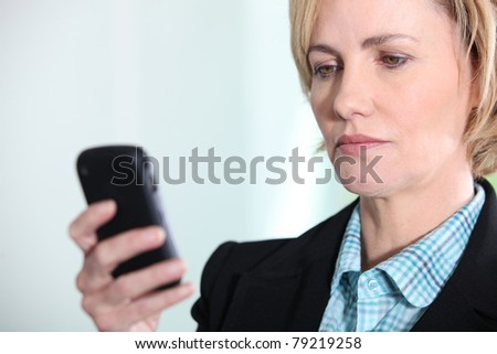 Blond woman looking at mobile telephone screen