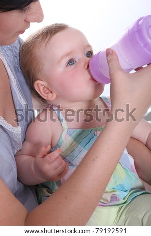 Mother feeding her baby water from a large baby bottle