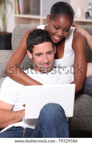 black woman is cuddling her boyfriend and doing computer