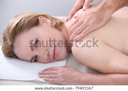 Woman being given a back massage and looking at us.