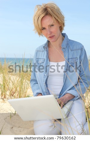 Woman on dunes with laptop computer