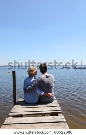 Couple sitting on the end of a pontoon with their arms around each other