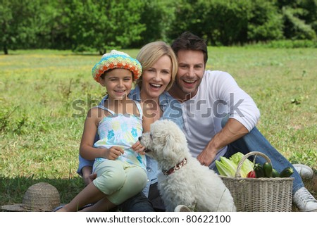 Parents and young daughter with dog and basket of vegetables