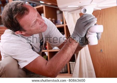 Man fitting the waste on a kitchen sink
