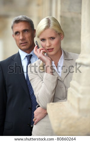 Business couple outside with a cellphone