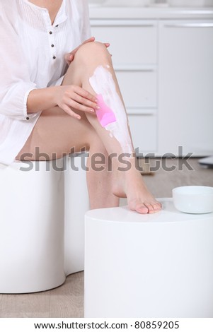 Woman using a hair removal cream on her legs