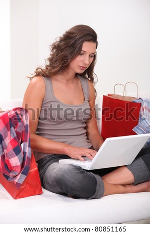 Woman at home shopping on-line surrounded by shopping bags