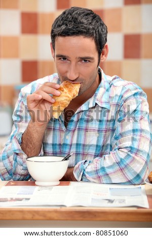Handsome man eating a croissant