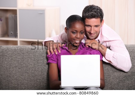 Couple sat at home looking at laptop computer