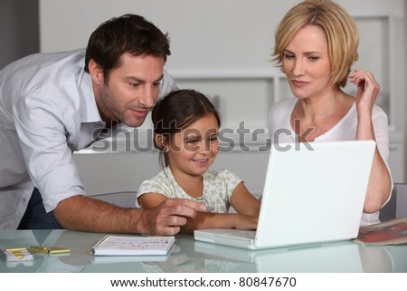 Young girl using a laptop computer with her parents