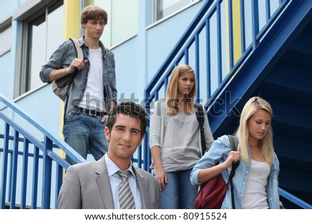 Three students walking down stairs alongside teacher