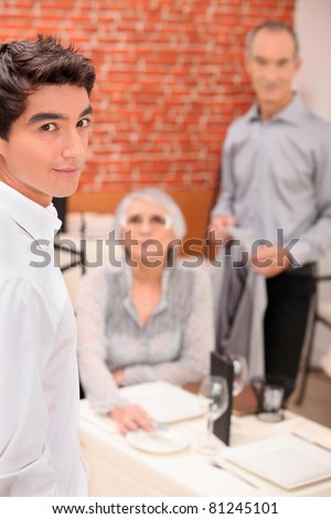 Young waiter serving an older couple in a restaurant