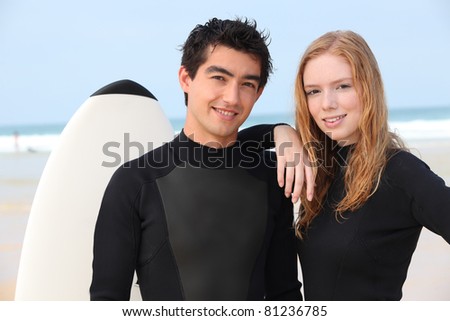 Young surfing couple in wetsuits