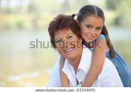 Young girl riding piggy-back on her grandmother\'s back