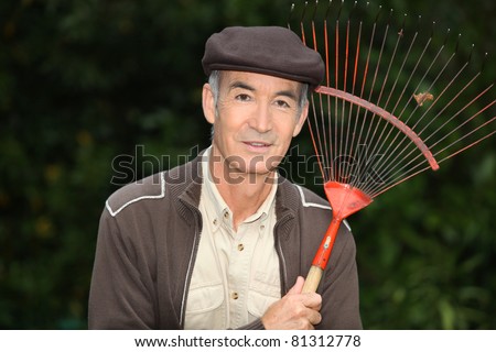65 years old man wearing brown clothes and holding a rake