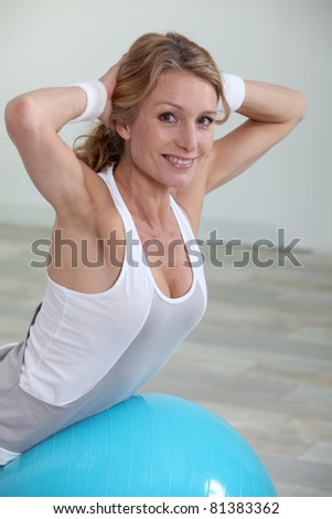 Blond woman at gym using balance ball