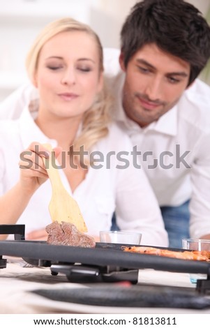Couple cooking surf and turf on a tabletop hotplate