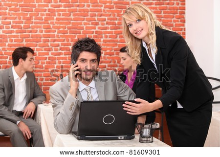 Waitress in a restaurant helping a man with his laptop computer
