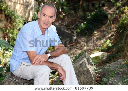 Older man sitting on a rock in a forest
