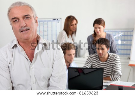 55 years old man watching us and  four young people focused on a laptop