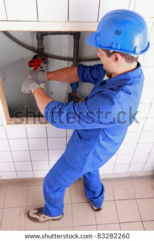 Plumber using a wrench on some large water pipes
