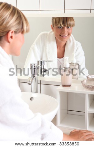 woman smiling through looking glass in her bathroom