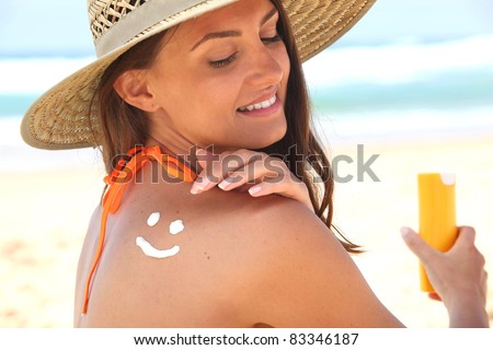 Woman sat on the beach applying sun cream
