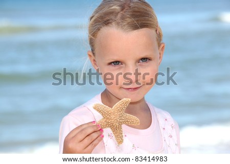 stock photo Young girl holding a starfish on the beach