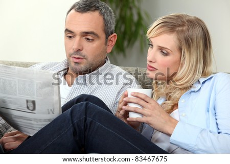 Couple reading newspaper on couch
