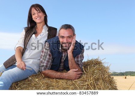 Farming couple sitting on a haystack