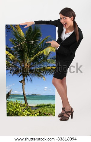 female travel agent showing poster of tropical beach