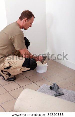 handyman putting glue and laying carpet
