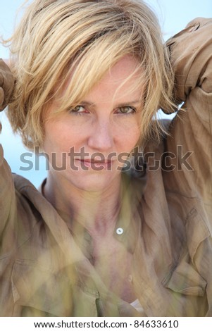 Closeup of woman with short blonde hair and arms behind her head