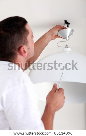 handyman fixate a lamp on the ceiling