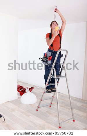 Handywoman fixate a lamp on the ceiling